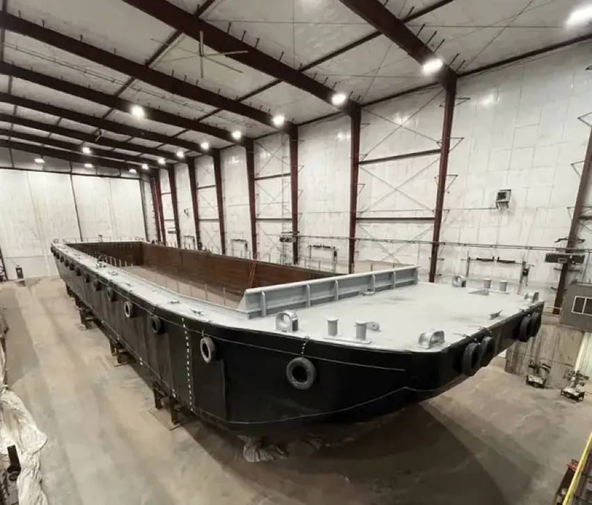 Coated steel barge hull under construction indoors