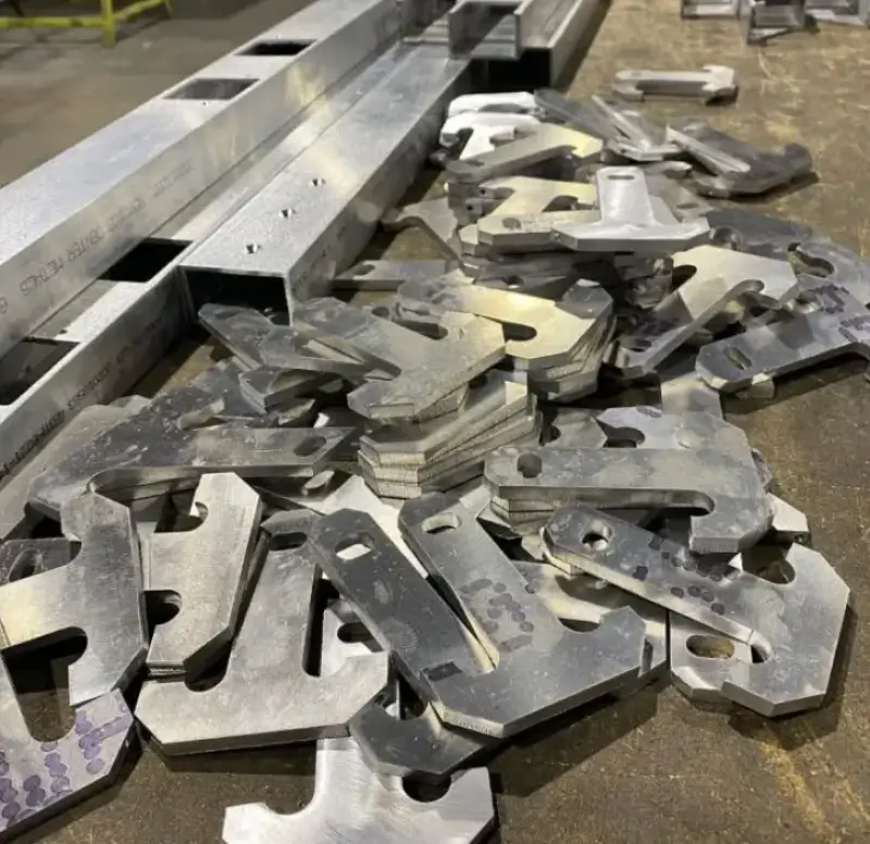 Laser-cut sheet metal brackets and beams piled on a workshop floor