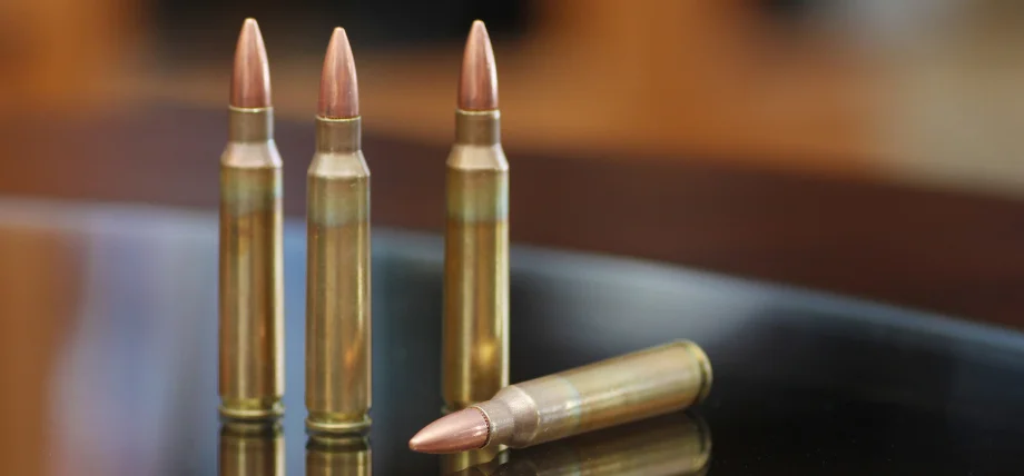 Three upright rifle cartridges with brass cases and copper-jacketed pointed bullets