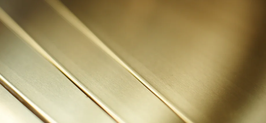 Close-up of parallel, highly polished brass strips displaying a smooth, reflective golden finish