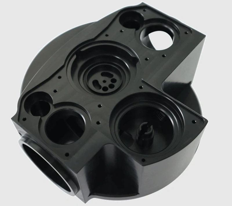 Black Delrin (acetal/POM) CNC-machined manifold housing with multiple precision-drilled ports and bores.