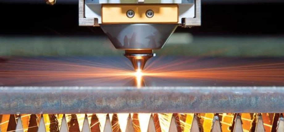 Close-up of a fiber laser cutting head actively piercing and cutting thick metal plate