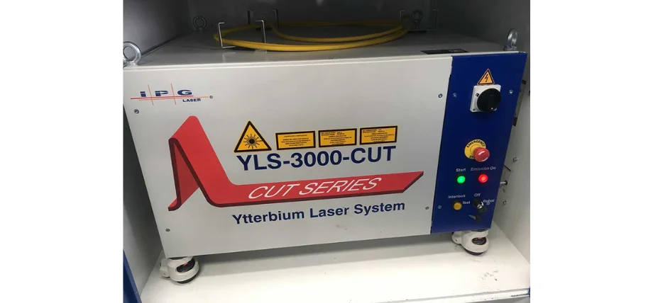 Ytterbium Laser System control unit with warning labels, start/emission buttons, and yellow fiber optic cable on top.