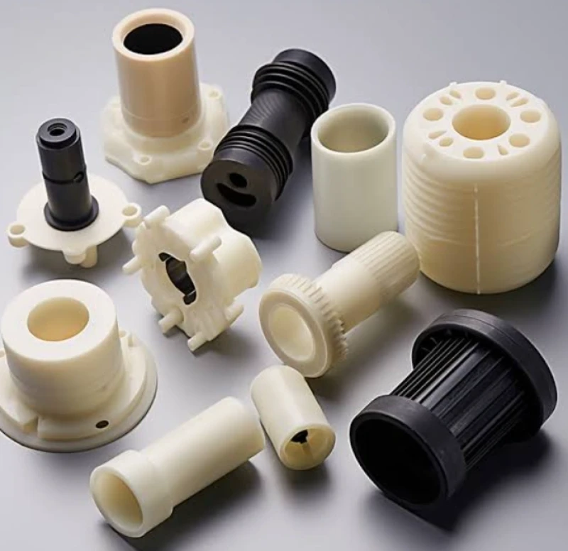 Precision-machined HDPE components, including bushings, flanges, gears, and threaded fittings in black and cream.