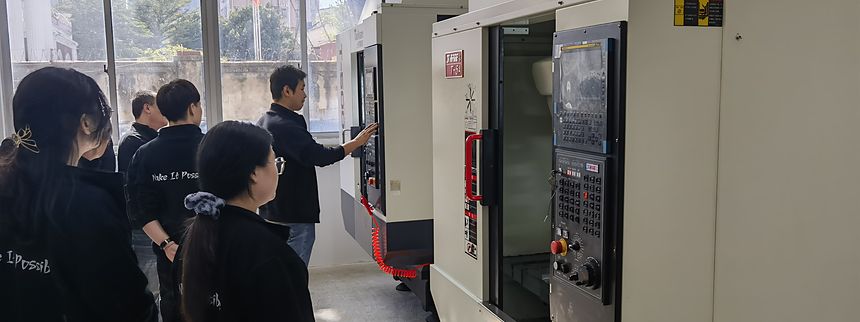 People gathered at the control panel of a CNC machining centre on the shop floor