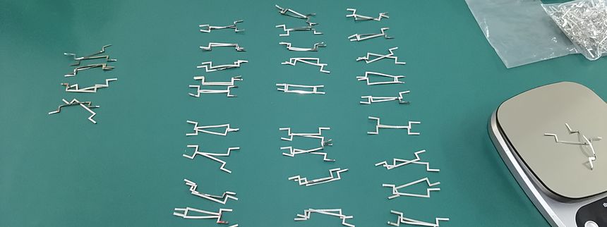 Rows of small machined parts laid out on a green inspection mat for counting