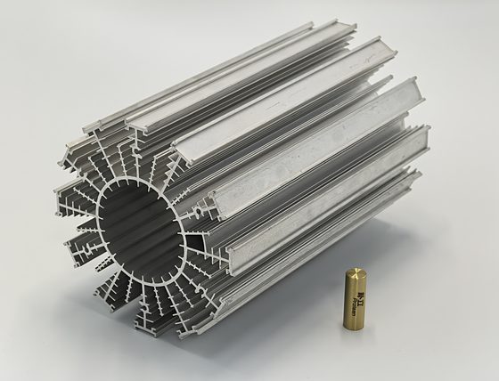 A machined aluminium heat sink with pin fins, next to a small brass machined fitting