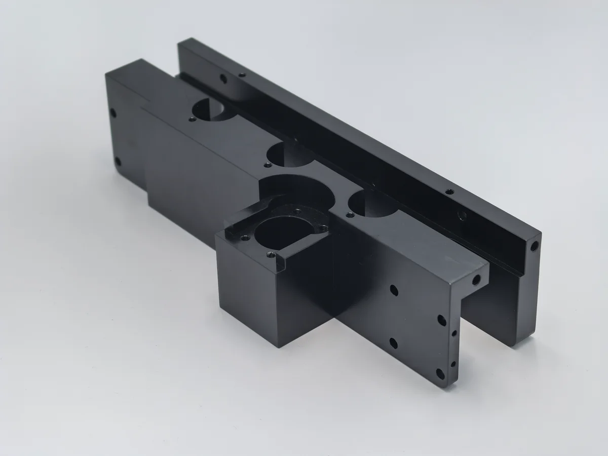 Black machined bracket with pockets and holes