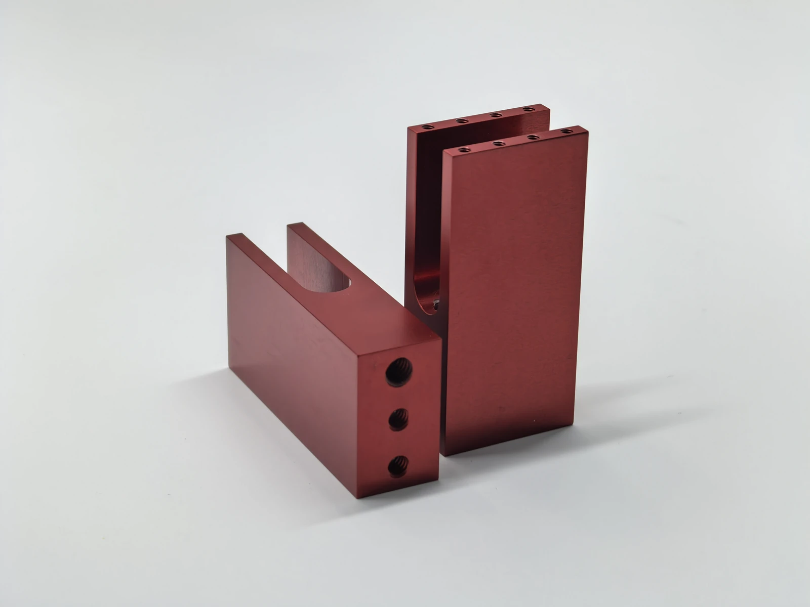 Red anodized bracket set with flat visible faces, open channels and threaded features