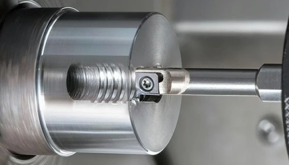 Grooving tool positioned against a cylindrical workpiece in a lathe