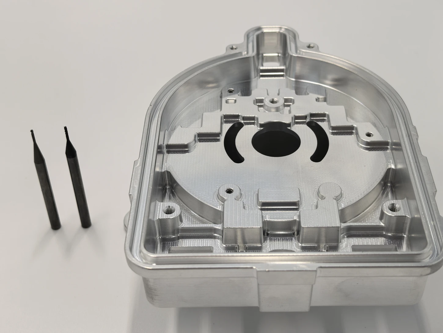 Detailed machined part shown beside small cutting tools