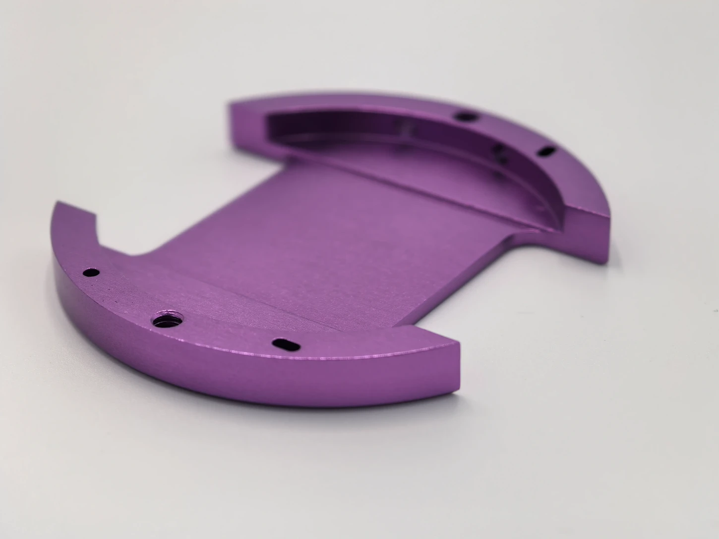 Purple anodized part with curved ends and mounting holes