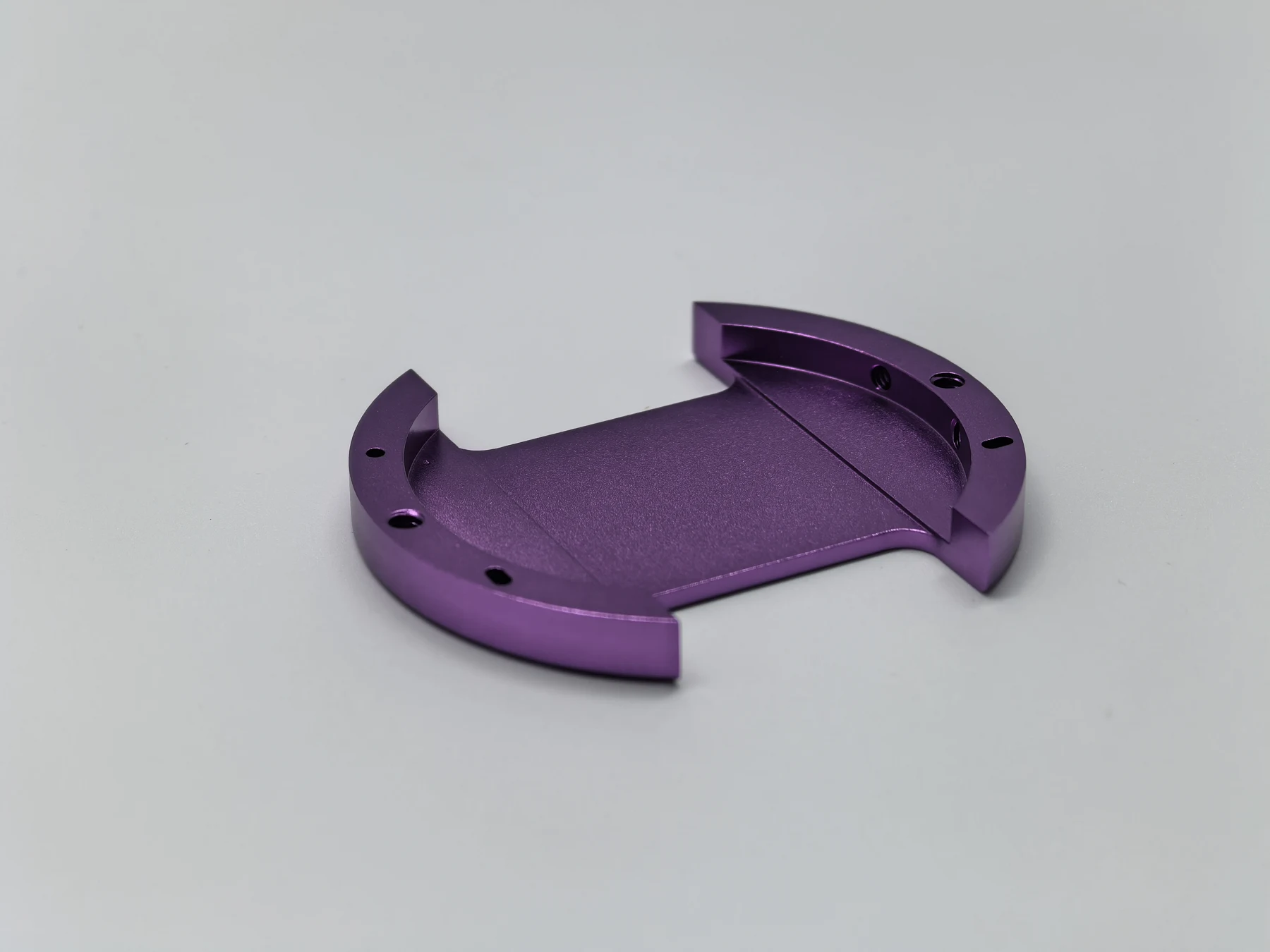 Purple anodized machined part with curved ends, threads and mounting holes