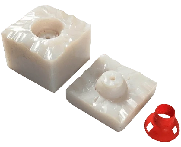 Open silicone mold halves beside a red component